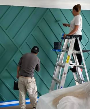 painters working on painting a detailed accent wall inside of a home
